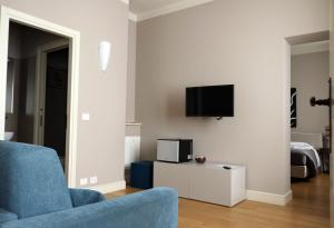 sala de estar con silla azul y TV en la pared en Albergo '900, en Quattordio