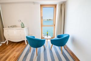 a room with two blue chairs and a table and a window at umag seafront seaview center apartment old town rentistra 3 in Umag