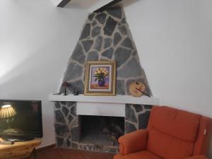 sala de estar con chimenea de piedra y TV en Casa Teatro Raices, en Taberno