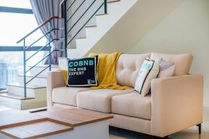 Arte Mont Kiara by Cobnb في كوالالمبور: غرفة معيشة مع أريكة عليها وسائد