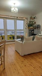 a living room with a white couch and windows at Private Double Bedroom in front of the Galway Port - Guest House in Galway