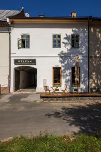 a white building with two benches in front of it at Welkam in Poprad