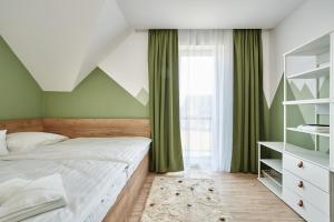 1 dormitorio con cama y cortinas verdes en Tatra Green en Veľká Lomnica