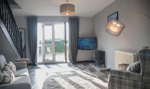 a living room with a couch and a tv and a window at White Rose Cottages, Near Thirsk in Thirsk