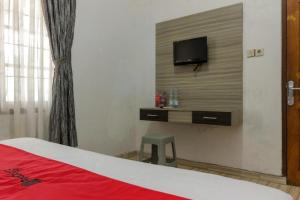 um quarto com uma cama e uma televisão na parede em RedDoorz @ Pantai Panjang Bengkulu em Pekansaptu