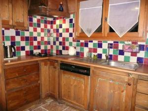 a kitchen with wooden cabinets and a sink and checkered wall at Très belle vue pour un chalet de 200 m2 in Arâches-la-Frasse
