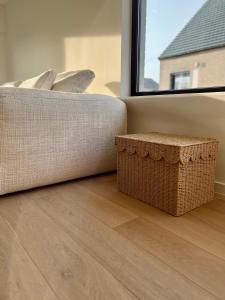 a couch sitting on a wooden floor next to a window at Maison Olive in Torhout