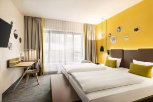 ein Hotelzimmer mit zwei Betten und einem Schreibtisch in der Unterkunft Vienna House Easy by Wyndham Berlin Prenzlauer Berg in Berlin