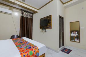 um quarto com uma cama e uma televisão na parede em FabHotel SR em Varanasi