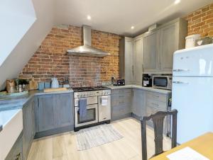 a kitchen with gray cabinets and a brick wall at Thomond House, Midhurst in Midhurst