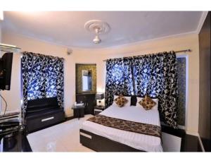 een slaapkamer met een bed met gordijnen en een televisie bij HOTEL MIDTOWN INN, Singrauli in Singrauli