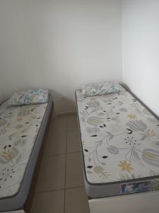 two beds sitting next to each other in a room at Sol Nascente Apartamentos - Pontal do Sul in Pontal do Paraná