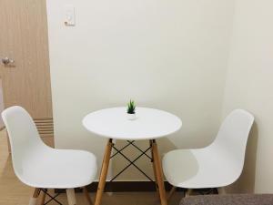 a white table with three chairs and a plant on it at Fairview Trees Residences Staycation in Manila