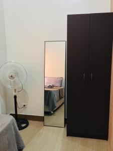 ein Schlafzimmer mit einem Spiegel, einem Bett und einem Ventilator in der Unterkunft Fairview Trees Residences Staycation in Manila