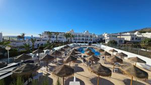 een groep rieten parasols en een zwembad bij Hotel El Puntazo I in Mojácar