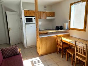 una cucina con tavolo in legno e una cucina con frigorifero di Olydea Montbrun-les-Bains a Montbrun-les-Bains