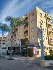 a building with a palm tree in front of it at TERPSICHORE Holiday Apts in Limassol