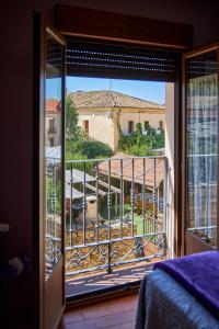 um quarto com uma varanda com vista para uma casa em Alojamiento Rural Fuente del Arca (Prádena del Rincón) em Prádena del Rincón