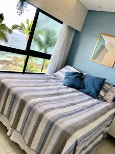a bedroom with a bed with a large window at apart hotel 2 quartos frente mar in Salvador