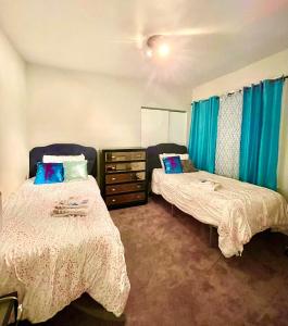 Lovely House in Atlantic City Weekly Deal في أتلانتيك سيتي: غرفة نوم بسريرين وخزانة وستائر زرقاء