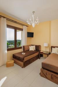 - une chambre avec deux lits, un canapé et un lustre dans l'établissement Costa Smeralda, à Sivota