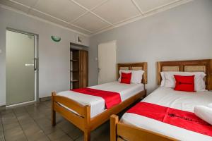 two beds in a room with red and white pillows at RedDoorz near Jam Gadang Syariah Bukit Tinggi in Bukittinggi