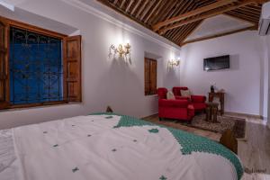 a bedroom with a bed and a red chair at Riad Dar Chama in Chefchaouene