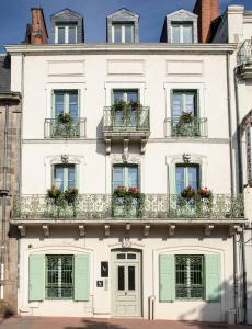 biały budynek z zielonymi drzwiami i oknami z kwiatami w obiekcie VILLA FLEURY - APPART'HÔTEL DE STANDING w mieście Limoges