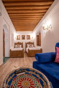 シェフシャウエンにあるRiad Dar Chamaのリビングルーム(ベッド2台、青いソファ付)