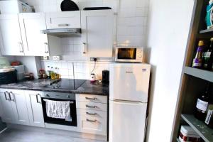 a kitchen with white cabinets and a white refrigerator at Central London Spacious Flat with 2 to 3 Bedrooms in London