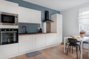 una cocina con armarios blancos y una mesa con sillas. en Evere EU Residence, en Bruselas