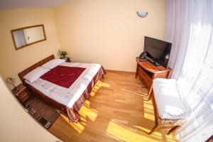 a small bedroom with a bed and a television at Hotel Uniwersytecki in Toruń