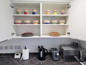 una cocina con estanterías llenas de platos y tazones en Little Hulton, Manchester 