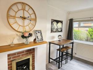a living room with a fireplace with a clock and a table at Little Hulton, Manchester 
