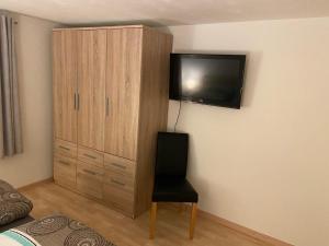 a bedroom with a chair and a tv on the wall at Ferienwohnung Dornau in Langkampfen
