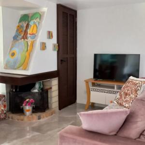 ein Wohnzimmer mit Kamin und Fernseher in der Unterkunft Casa de 3 Quartos em Garopaba - Bairro Ferraz in Garopaba