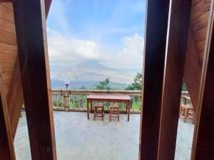 a table and chairs on a balcony with a mountain view at The Panorama Batur Camp in Kintamani