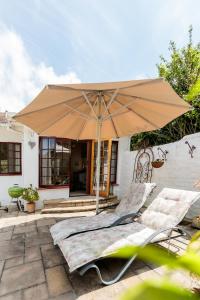 a patio with an umbrella and two lounge chairs at Hillingdale on Alexandra in Cape Town