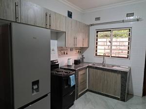 a kitchen with a black refrigerator and a sink at Edmut Apartments in Lusaka