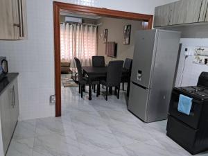 a kitchen and dining room with a table and a refrigerator at Edmut Apartments in Lusaka