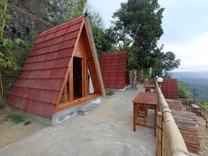 una pequeña casa con techo rojo y mesa en The Panorama Batur Camp, en Kintamani