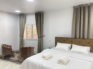 1 dormitorio con 2 camas con sábanas blancas y ventana en استراحة الشرف ALSHARAF, en Al ‘Aqar