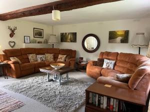 uma sala de estar com dois sofás castanhos e uma mesa em Cottages at Woodlands, Dormer em Wareham