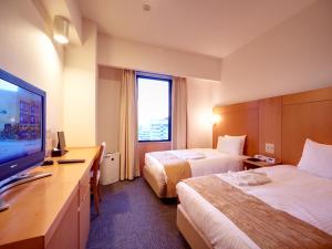 een hotelkamer met 2 bedden en een flatscreen-tv bij Hotel Rocore Naha in Naha
