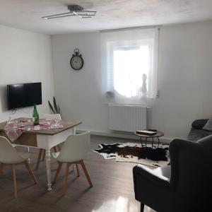 - un salon avec une table, des chaises et une télévision dans l'établissement Ferienwohnung mit WiFi und 2 Schlafzimmern - b45533, à Ipsheim