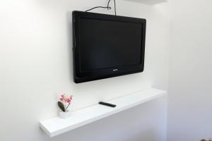 a flat screen tv hanging on a white wall at Ouro Preto Suítes in Ouro Preto