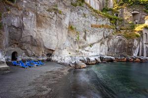 a group of chairs sitting on a beach next to a mountain at Grand Hotel Cocumella in Sant'Agnello