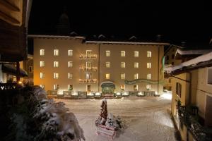 un grande edificio di notte con neve sul terreno di Hotel Du Grand Paradis - 1899 Auberge Boutique a Cogne