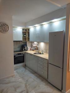 cocina con armarios blancos y nevera blanca en Apartman Star LUX, en Kula