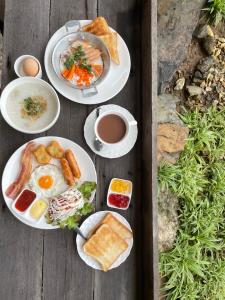a table with plates of breakfast foods and a cup of coffee at Baanrimfai Homestay in Ban Thung Sang